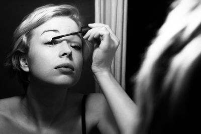 Woman applying mascara looking at mirror