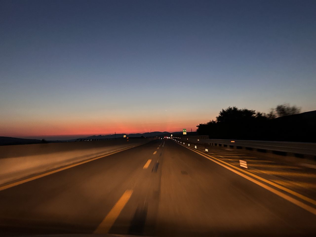 transportation, road, sky, horizon, dusk, highway, motion, sunset, mode of transportation, no people, evening, nature, night, light, long exposure, motor vehicle, car, the way forward, illuminated, travel, vanishing point, speed, diminishing perspective, street, road marking, on the move, traffic, blurred motion, outdoors, sign, darkness, city, marking, landscape, copy space, symbol, headlight, journey, land vehicle, light trail, infrastructure, environment