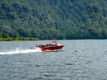 Boat sailing on sea against trees