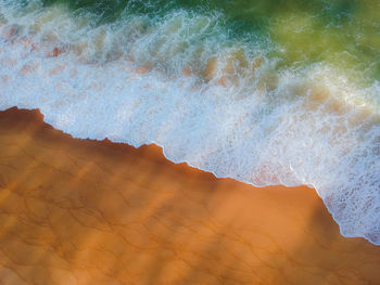 High angle view of waves reaching on shore at beach