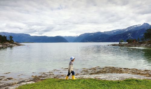 Boy standing in lake against sky