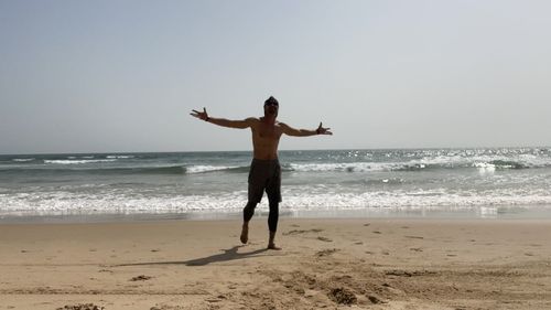 Full length of woman walking on beach against clear sky