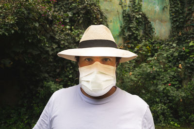 Portrait of young man wearing hat against plants