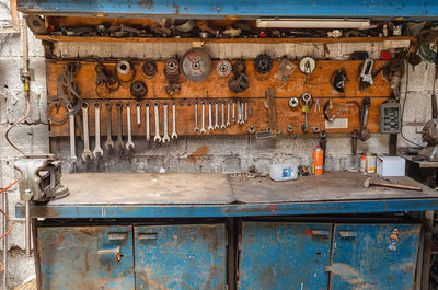 Old collection of various repair tools hangs on wall above table. workshop with tools.