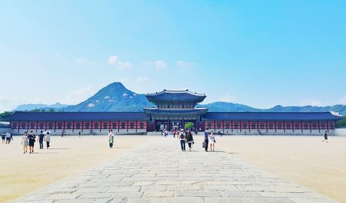 People on footpath at gyeongbokgung against sky