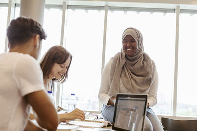 Smiling university students studying together in classroom