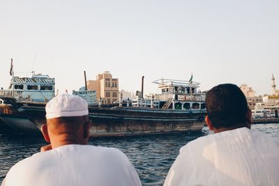 Rear view of man and woman looking at harbor against clear sky