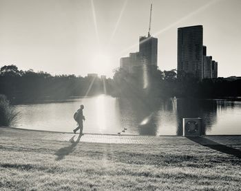 Man running on river in city against bright sun