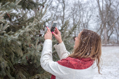 Woman holding mobile phone in snow