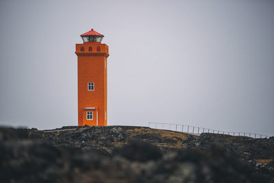 Lighthouse by sea against clear sky