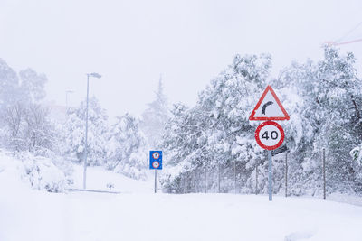 Road sign on snow covered land against sky