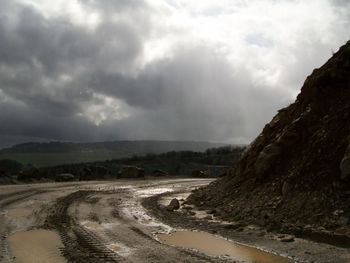 Scenic view of road by land against sky during rainy season