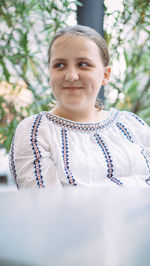 Portrait of young woman standing against trees