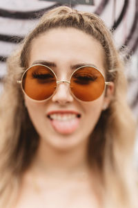 Close-up of young woman wearing sunglasses while sticking out tongue