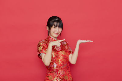 Portrait of a smiling young woman against red background