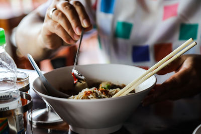 Midsection of person having food called noodles  on the table