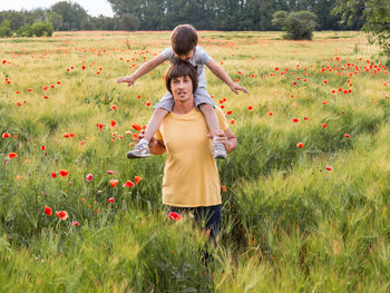 Laughing boy, his father. happy kid smiles. dad and son on rye field with red poppy flowers. family