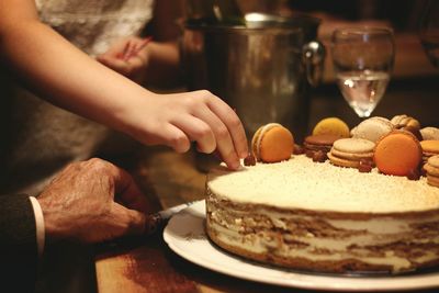 Close-up of hand holding cake on table