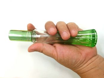 Close-up of hand holding bottle against white background