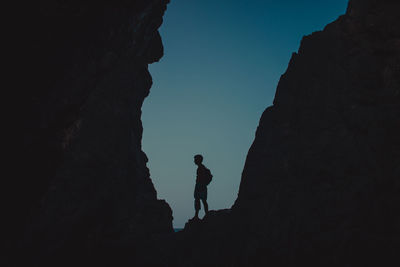 Silhouette man standing on rock formation during sunset