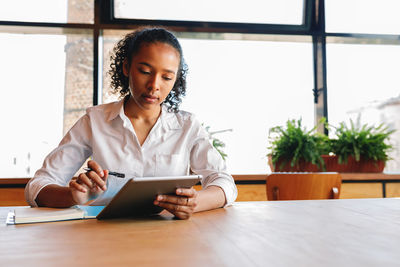 Young woman using phone while sitting on table