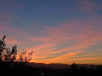 Silhouette trees against dramatic sky during sunset