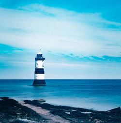 Lighthouse by sea against sky