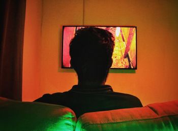 Rear view of woman standing against wall at home