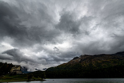 Scenic view of sea and mountains against storm clouds