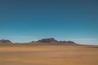 Scenic view of desert against clear blue sky