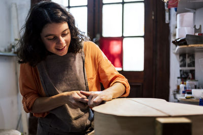 Mid adult woman looking down while sitting in kitchen