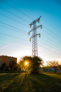 Electricity pylon on field against sky during sunset