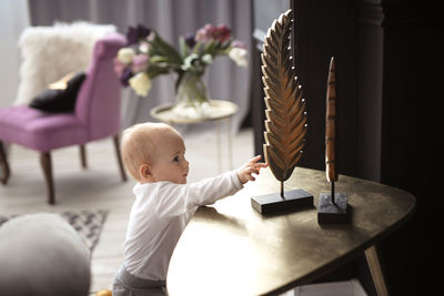 Baby stands at support and reaches out to things on the table, concept of child development  