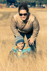 Portrait of mother and son smiling on grassy field