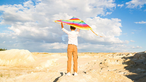 A boy of 8-9 years old happily launches kite into the sky.