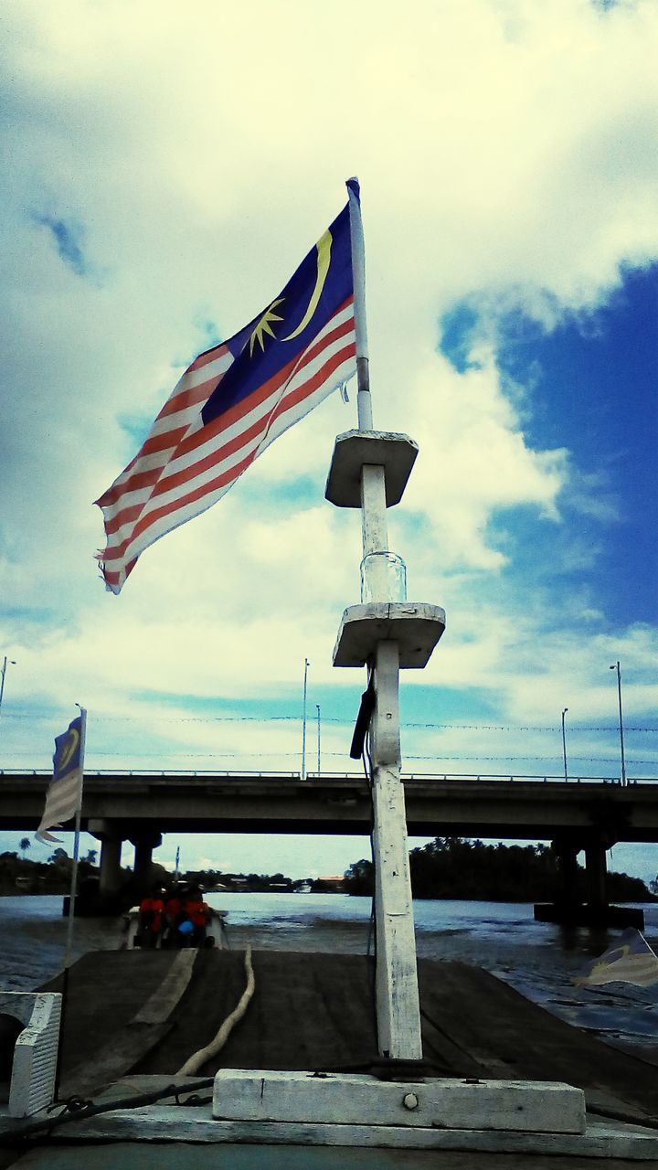 sky, built structure, cloud - sky, flag, architecture, water, cloudy, cloud, pier, sea, identity, patriotism, national flag, transportation, railing, building exterior, day, outdoors, nautical vessel, american flag