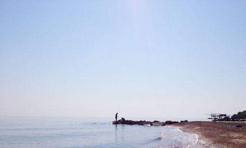 Man fishing in sea against sky