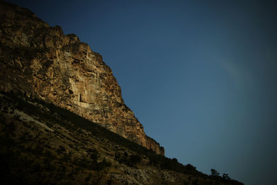 Low angle view of rock formation against clear blue sky