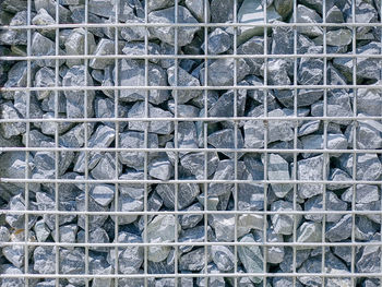 Full frame background of gravel stones wall with metal wire mesh