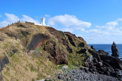 Scenic view of cliff by sea against blue sky