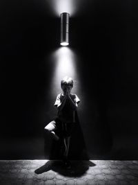 Woman sitting on wall in illuminated room