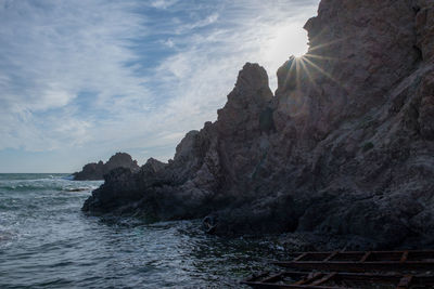 Rock formations by sea against sky