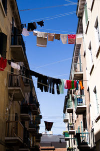 Low angle view of clothing hanging from buildings against the sky