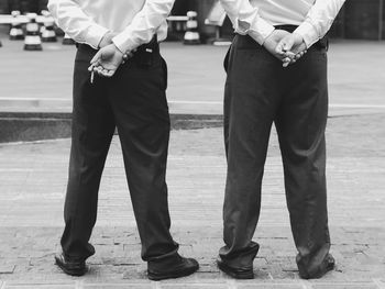 Low section of police men smoking cigarette while standing on street