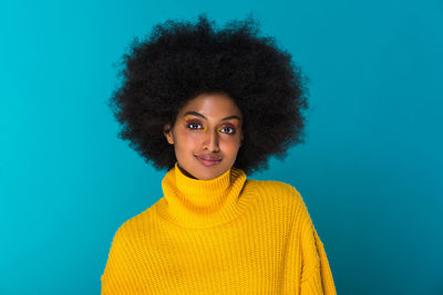 Portrait of smiling young woman standing against blue background