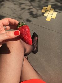 Low section of woman holding strawberries