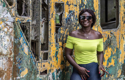 Happy africa woman from ghana stands in front of an old broken helicopter