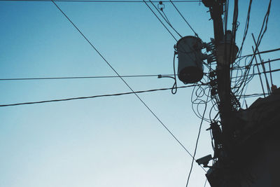 Low angle view of electricity pylon against clear sky