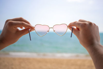 Close-up of hands holding heart shape on beach