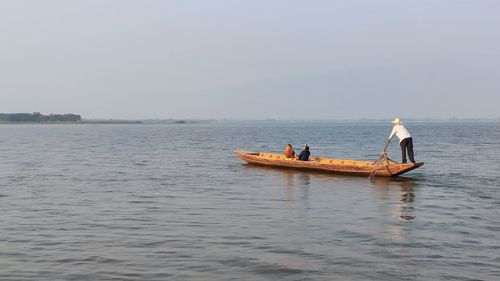 People on boat in sea against sky